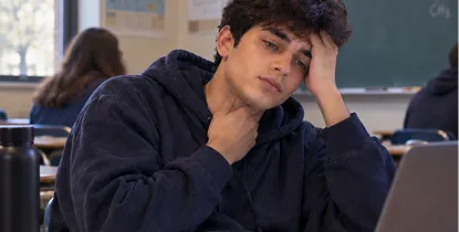 Student in a classroom viewing a signed doctor's note on his phone