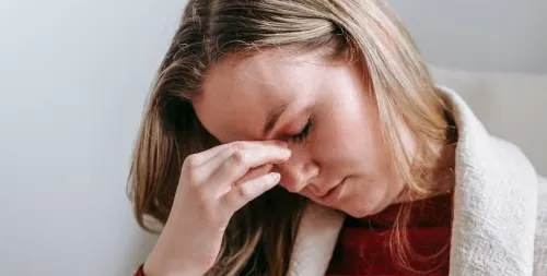 Woman pinching the bridge of her nose during a migraine
