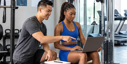 Personal trainer reviewing a laptop with a client at the gym
