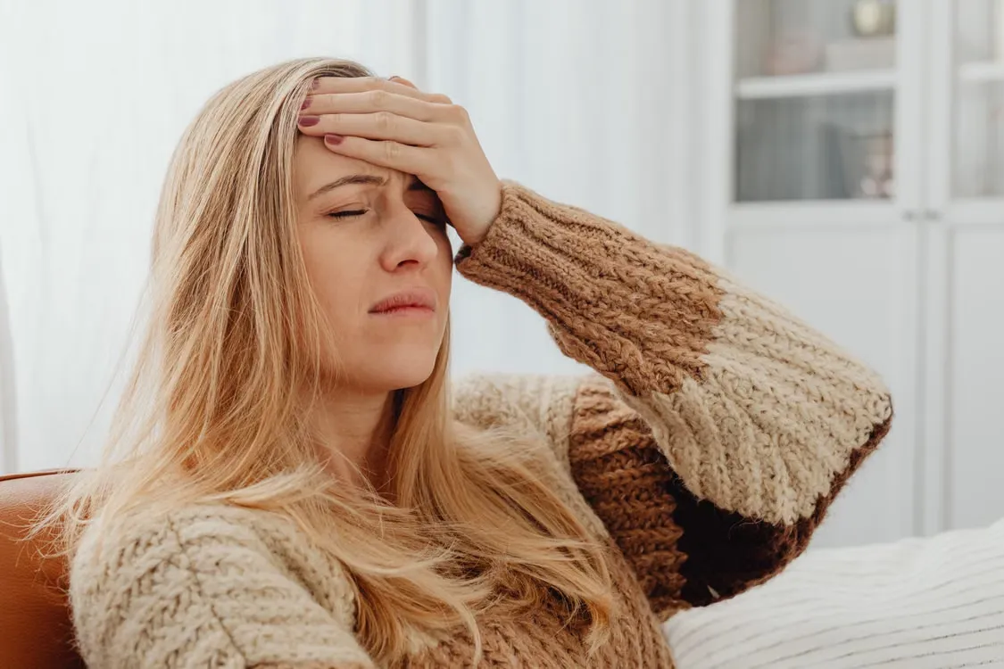 Woman pressing a hand to her forehead with a severe headache