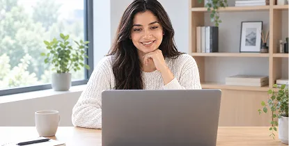 Smiling woman working on a laptop at a home desk